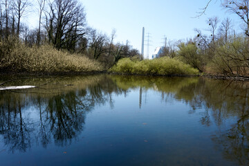 small blue lake with colorful trees in sunshine under blue sky