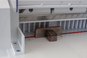 wooden pusher on automatic paper stack or label cutting machine, professional cutter, printing shop or workshop equipment.