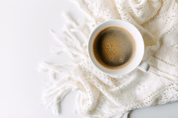 Cup of coffee on white table with a crochet blanket.