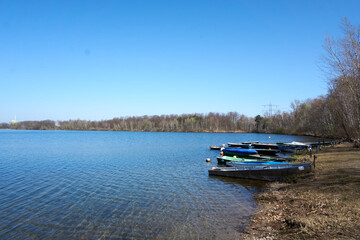 several boats in different colors are lying at a lake