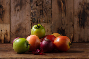 Green tomatoes, red onions on rusric background. Farmer fresh organic product. Vegan eco-friendly no animal food, copy space