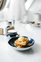 breakfast of Viennese waffles with mousse and cappuccino on the table at the hotel