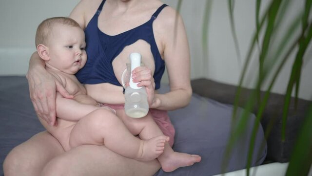 Young Mother With Newborn Cute Infant Naked Baby Boy, Holding Him On Arms, Using Breast Pump Hugging And Breastfeeds With Breast Milk. Healthy Child, Concept Of Hospital And Happy Motherhood. Nursery