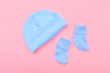 baby hat and little socks on pastel pink background .