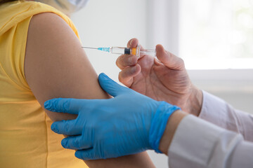 Doctor applying a vaccine on a woman's arm .