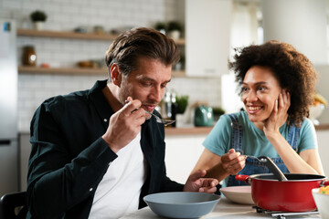 Boyfriend and girlfriend eating lunch together at home. Husband and wife enjoying in delicious food.