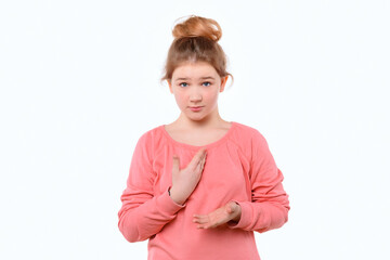 Cute young girl in pink casual sweatshirt points at herself with hand in surprise. White background