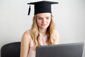 Woman student takes an online exam, defends a diploma behind a laptop. Online education, graduation concept