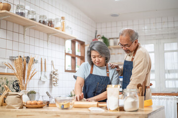 Asian senior couple helping each other for homemade bakery cooking.