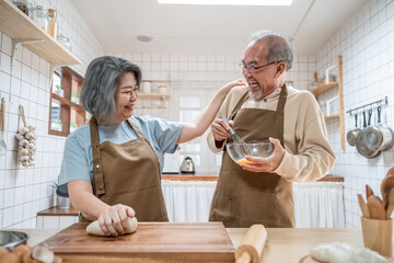Fototapeta na wymiar Asian senior couple helping each other for homemade bakery cooking.