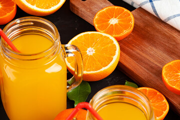 Glass of orange juice and cut oranges on table