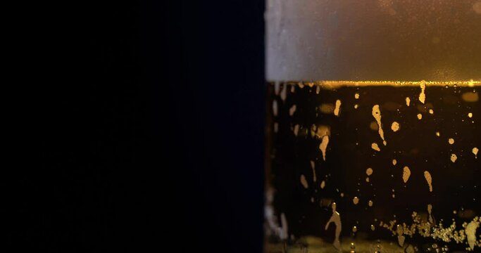 Cold beer with drops and bubbles. Fresh alcohol with soft foam in glass cup on brown background. Pub. Panorama of beer glass