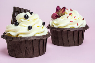 Set  cupcakes with vanilla cream decorated with roses  and chocolate on pink background with  copy space for text .