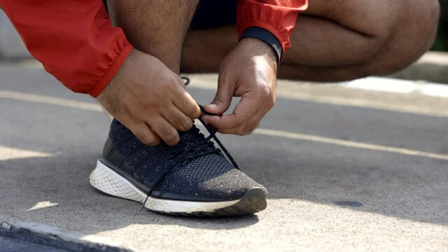 Runners tie their shoelaces prepared to run outdoors. Young asian man wearing sportswear running outdoor.Training athlete work out at outdoor concept.