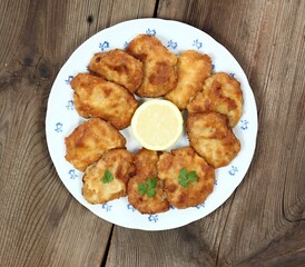 Pork schnitzels served on the plate.  Decorated with sliced lemon and parsley. Brown rustic table. Top view, flat lay.