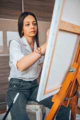 Beautiful talented female artist painting at her home.