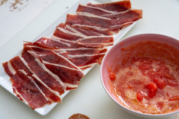 Jamón ibérico en fuente y salsa de tomate. Iberian ham in a bowl and tomato sauce.