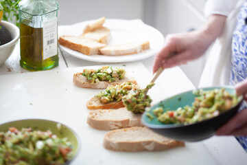 Mujer preparando aperitivos y pinchos, tapas de España, guacamol. Woman preparing appetizers and pinchos, tapas from Spain, guacamole.