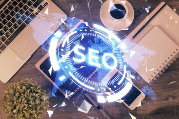 Double exposure of SEO hologram drawing over desktop. Top view. Search optimization concept.