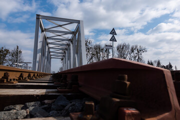 A close-up on rails and a railway bridge. Perspective photo taken on a sunny day.