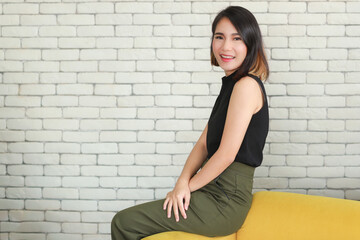 Portrait of young and cute Asian woman sitting sofa in self-confident pose and smile with friendly and happy face.