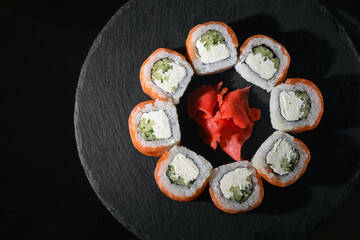 classic Philadelphia rolls in smoked salmon with salmon caviar. japanese sushi on a slate board on...