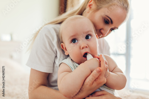 Mother's day. Woman playing with her newborn baby son at home. Family having fun. Infant biting toy