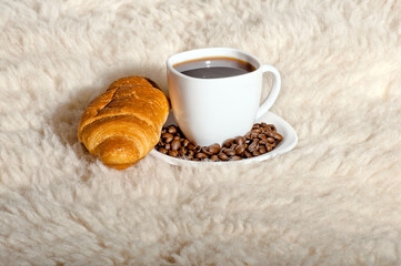 Croissant with coffee and beans on fur background