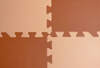 Four pieces of foam plastic flooring in the playroom. Beige and brown puzzle