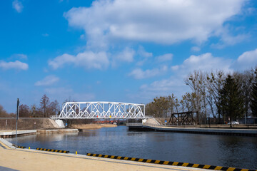 White railway bridge over the river against the background of blue sky. Made at noon on a sunny day. City of Pisz