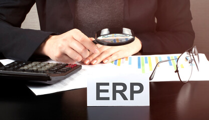 Close up Business woman using calculator and charts do math finance on the wooden desk office and business working background with text ERP