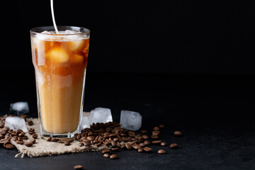 cold iced coffee with milk or cream on a dark background coffee beans, summer drink