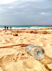 A plastic bottle lies on the beach and pollutes the sea and the life of marine life.