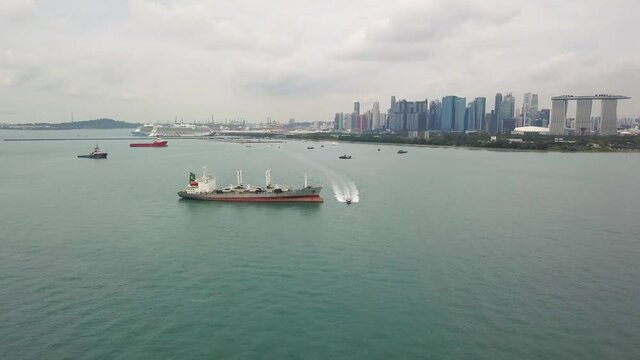 Drone shot of boat moving in water with Singapore skyline