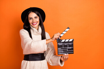Portrait of beautiful cheerful woman holding clapper action casting time isolated over bright...