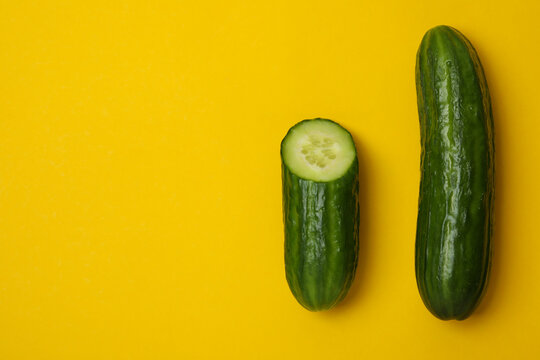 Ripe cucumber and half on yellow background