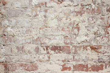 A brick wall with crumbling plaster from old age. The influence of wind and precipitation on materials in construction.