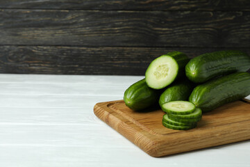 Board with ripe cucumbers on white wooden table