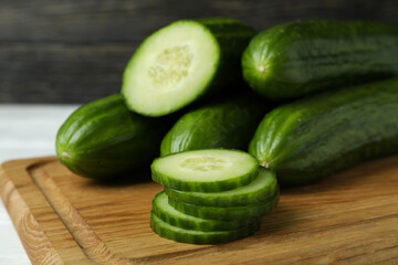 Board with ripe cucumbers on wooden background, close up