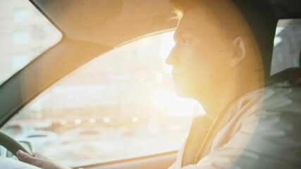 A young Asian guy in a light jacket, drives a car. A man driving a car. City driving with a right-hand drive. A young driver is mastering city driving skills. sunny day 