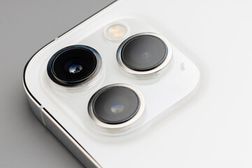 Fototapeta premium Close up of triple-lens camera of modern smartphone on gray background