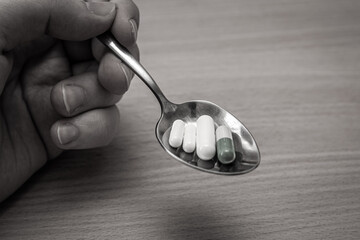 Hand holding a spoon of drugs. Eating antidepressants concept