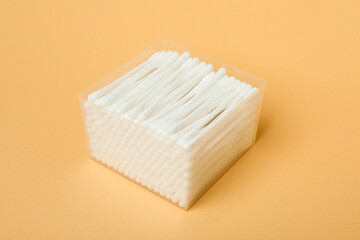Plastic box with cotton swabs on beige background