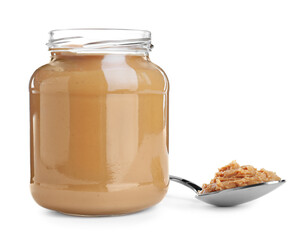 Glass jar and spoon with tasty peanut butter on white background