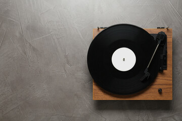Turntable with vinyl record on grey background, top view. Space for text