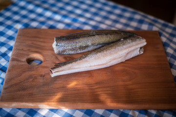 raw fish on a wooden board, healthy vegetarian food, frozen hake (Merluccius) on a kitchen board, fish cooking