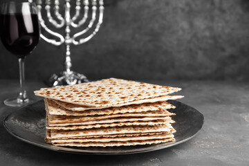 Stack of traditional matzos near red wine on grey table