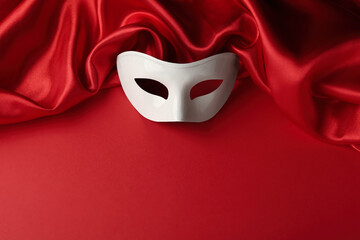White theatre mask and fabric on red background, above view. Space for text