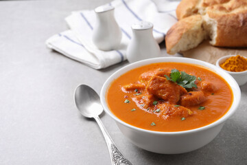 Bowl of delicious chicken curry on light grey table, space for text
