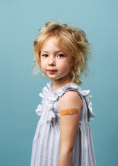 Portrait little girl with adhesive plaster on shoulder posing isolated. Covid-19 prevention